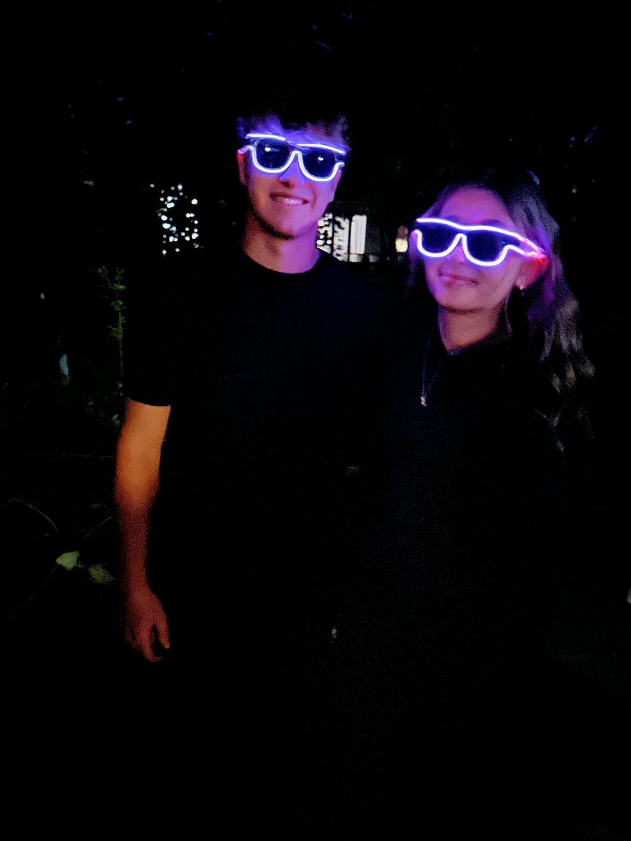 Two friends wearing white and purple Sunglasses At Night glasses at night
